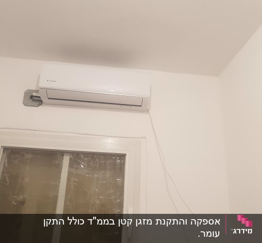 מזגן מותקן על קיר מעל חלון